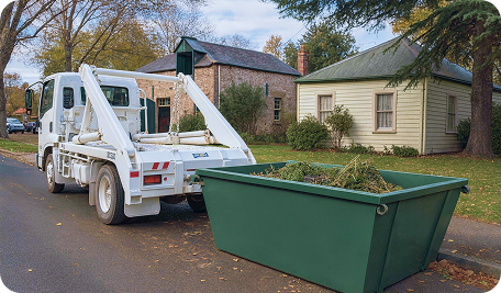 Skip Bin Hire Launceston truck collecting a filled skip bin from a residential home for waste disposal