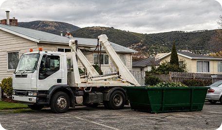 Skip Bin Hire Hobart truck collecting a full skip bin filled with green waste and leaves at a rural property in Tea Tree, providing efficient on-site bulk waste removal services